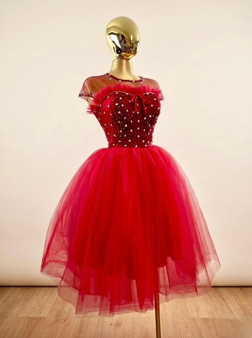 The Radiance-This vibrant red tulle gown is a testament to technical skill, featuring hundreds of rhinestones and pleating. The structured bodice is designed to provide a flawless silhouette while feeling light-as-air feel. A bold choice for the graduate