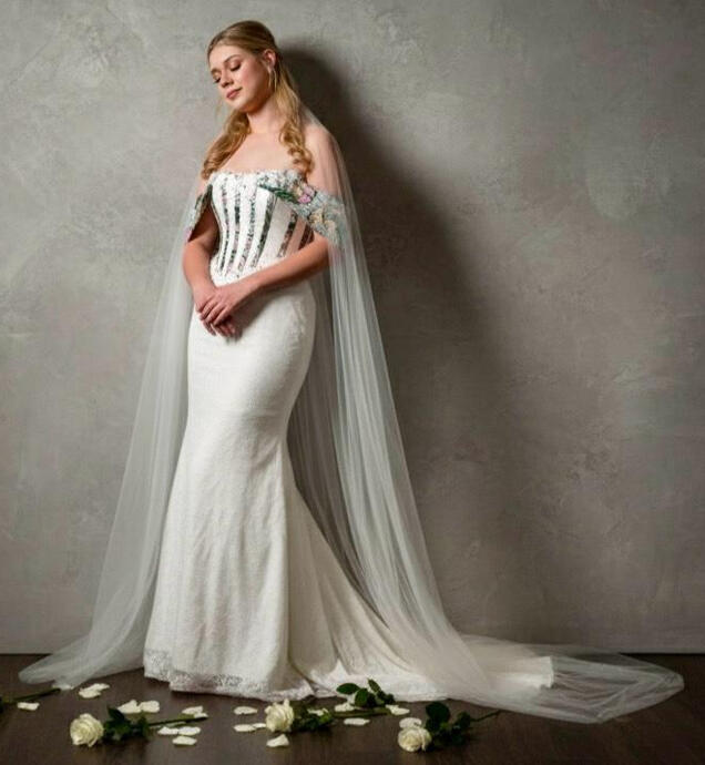 Ankara Infused-This bespoke bridal look is precision-made, featuring a mix of Ankara-inspired floral patterns and lace. The off-the-shoulder silhouette and floor-length tulle cape create a dramatic effect.